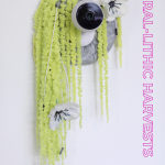 Yellow and white sculpture with a camera and the title of the exhibition.